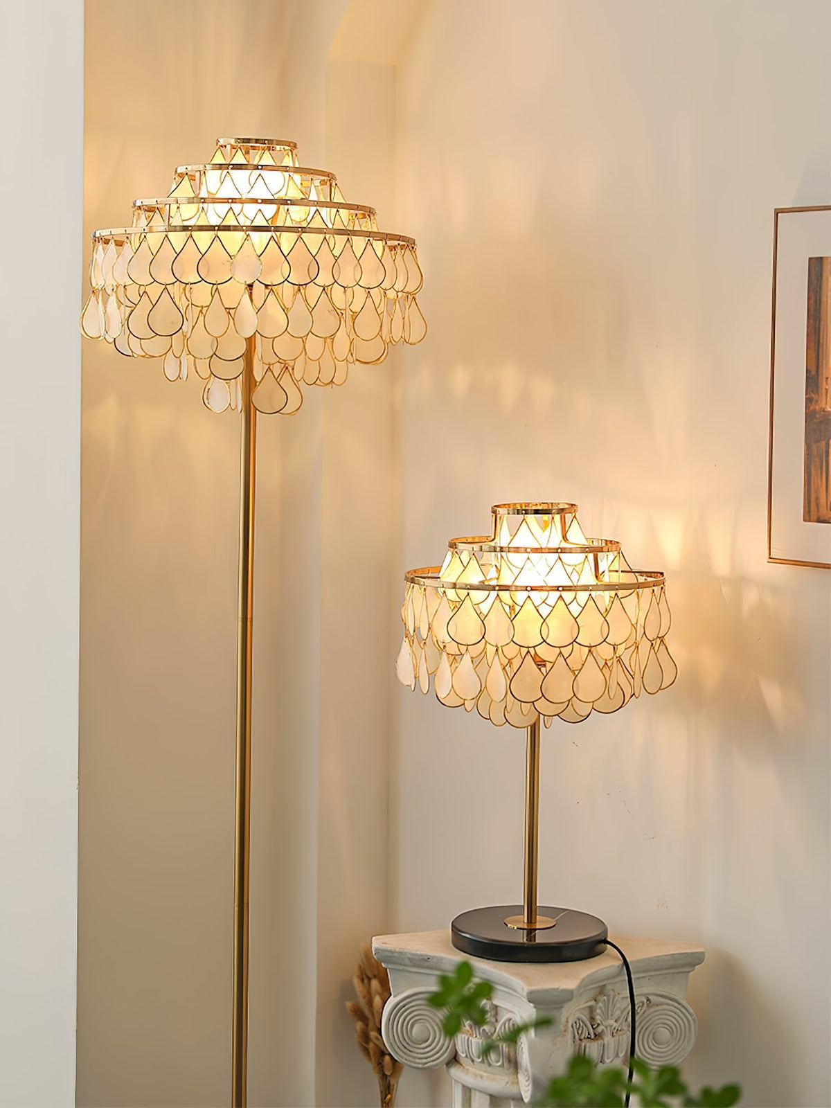 Clérachic table lamp and a taller floor lamp glowing in a warm hallway beside a small plant stand and framed art.