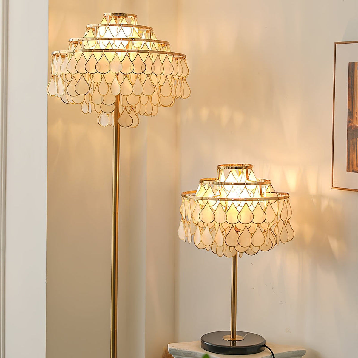 Clérachic table lamp and its taller floor-lamp companion glowing in a room with tall sheer-curtained windows.