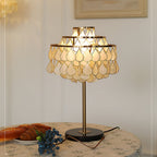 Dressed with a floral cloth, croissants and scattered blueberries, the round table holds the glowing Clérachic table lamp.