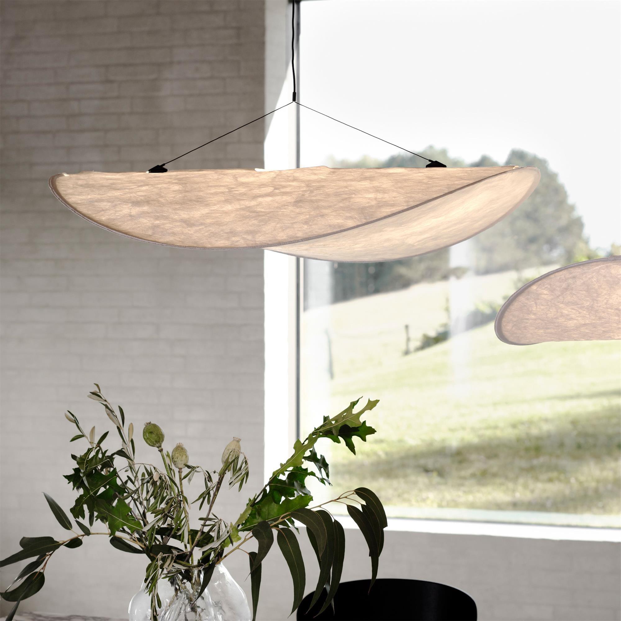 White paper pendant lamp glowing above a modern dining setup