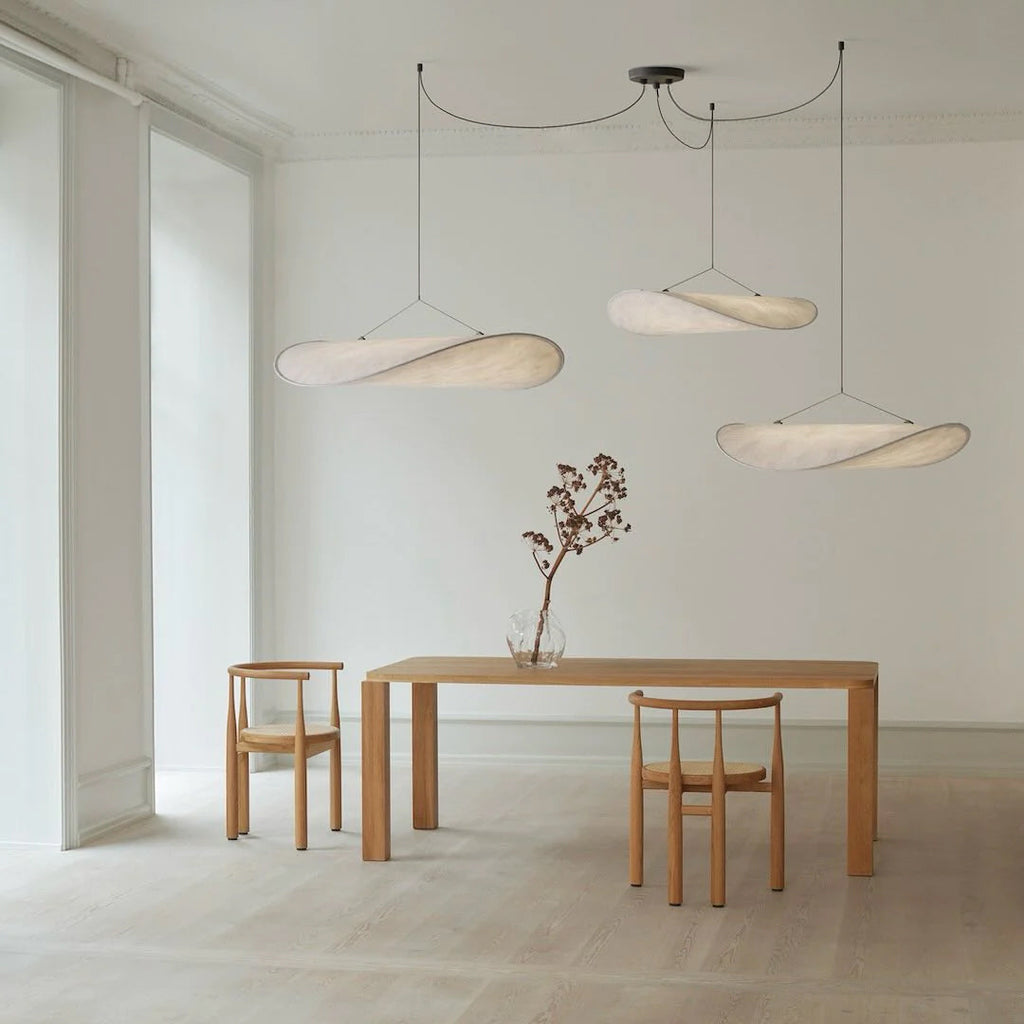 Paper pendant lamp suspended above a minimalist dining space