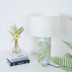 Clérachic table lamp shown closer in, fern fronds and the flower vase visible either side of the marble base.