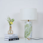 Clérachic table lamp shown with extra headroom above the drum shade, books, vase and fern fronds still in frame.