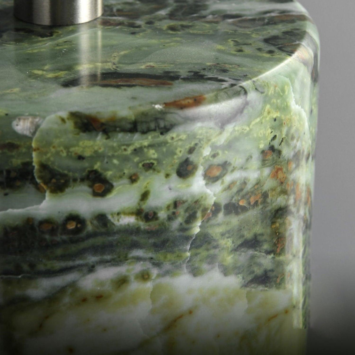 Extreme close-up of the Clérachic table lamp's green marble base, showing the depth of its natural veining.