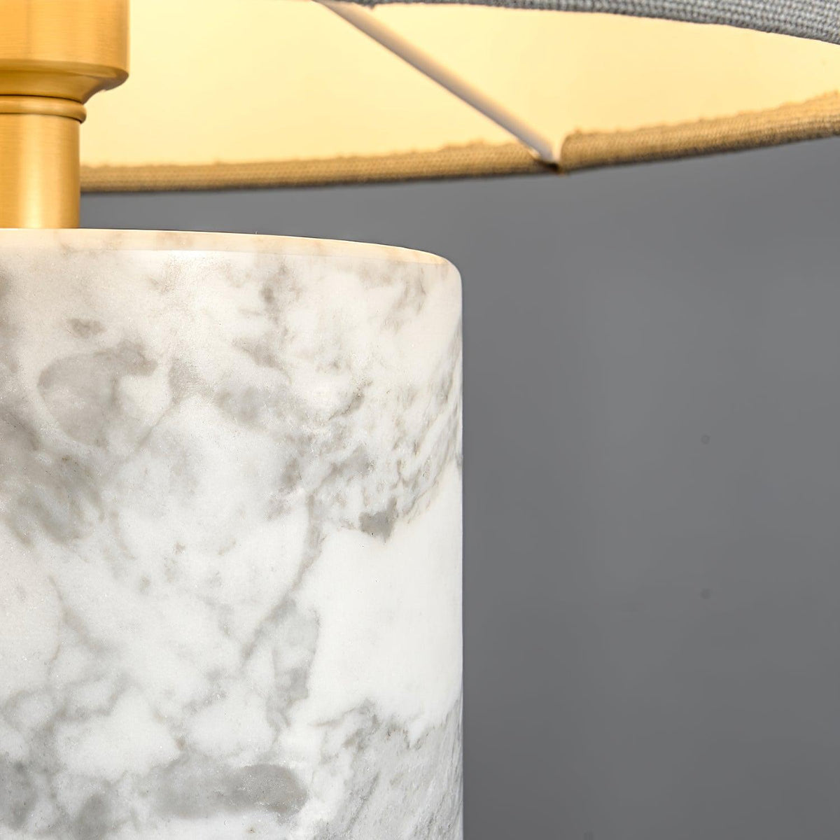 Close-up of the Clérachic table lamp's green marble base, showing the stone's veining and the brass cap at its rim.