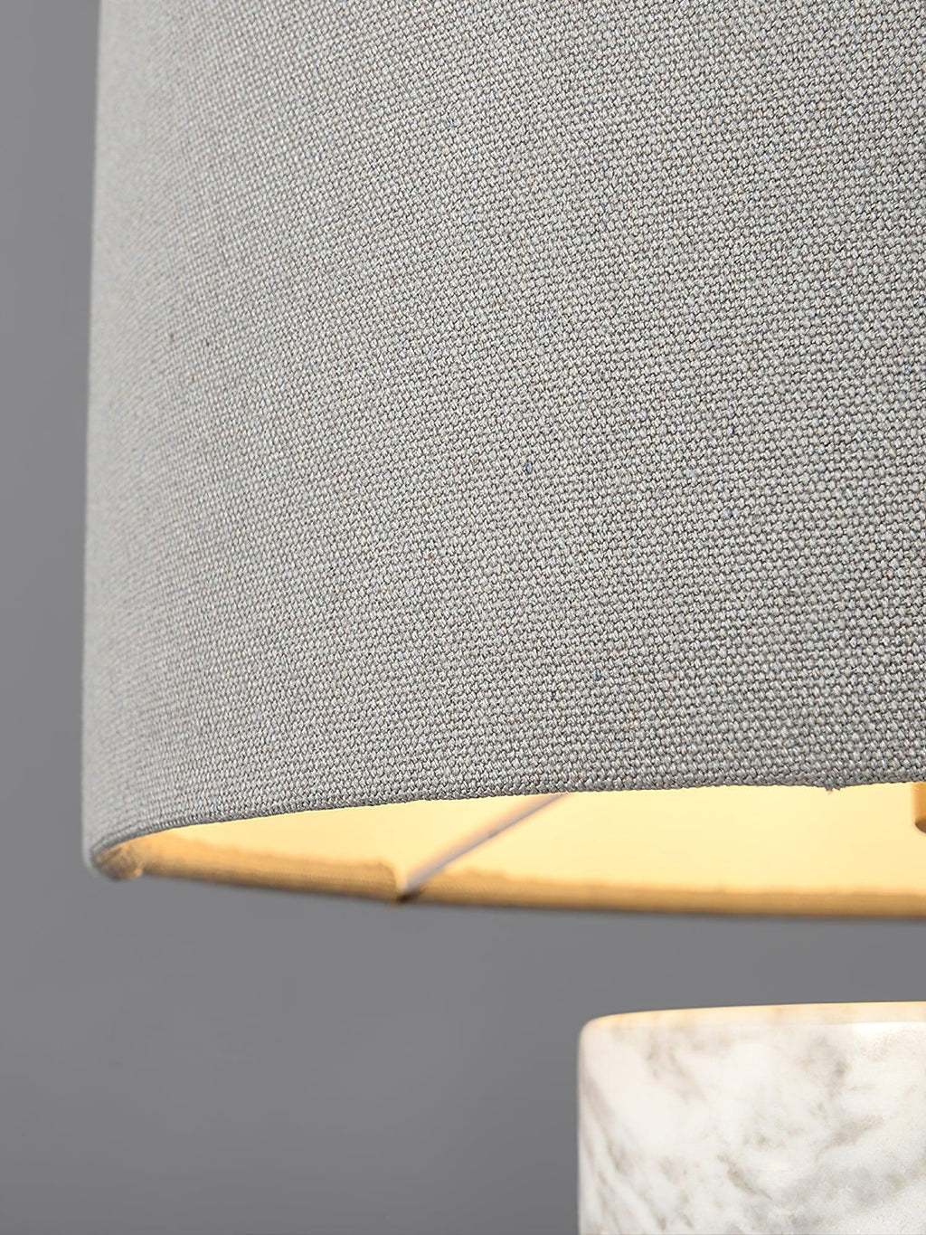 Close-up of the Clérachic table lamp's woven drum shade edge and brass gallery, shown against a plain grey backdrop.