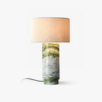 Clérachic table lamp on a plain background, its green marble cylindrical base topped with a white drum shade and trailing cord.