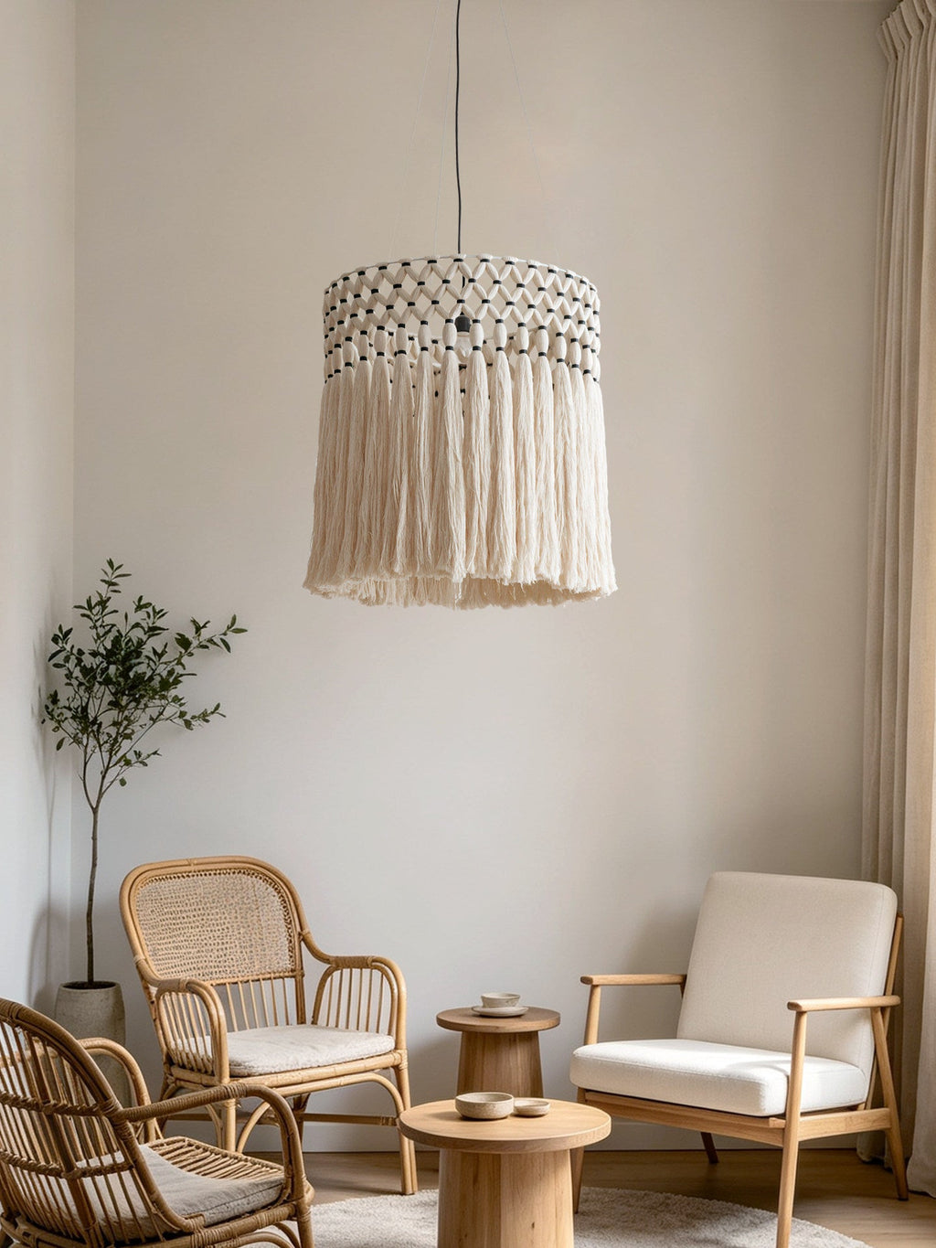 In a living room with rattan armchairs and a round wood side table, this Clérachic pendant glows warm and cream-toned.