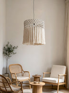 In a living room with rattan armchairs and a round wood side table, this Clérachic pendant glows warm and cream-toned.
