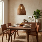 Woven leather chairs and a leafy plant surround a wood table lit by this rattan Clérachic pendant.