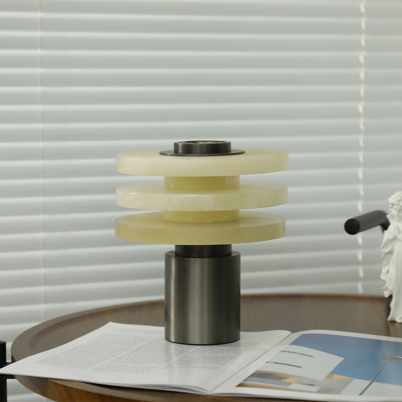 The unlit lamp in daylight from the side, its three alabaster discs spaced evenly above the metal base