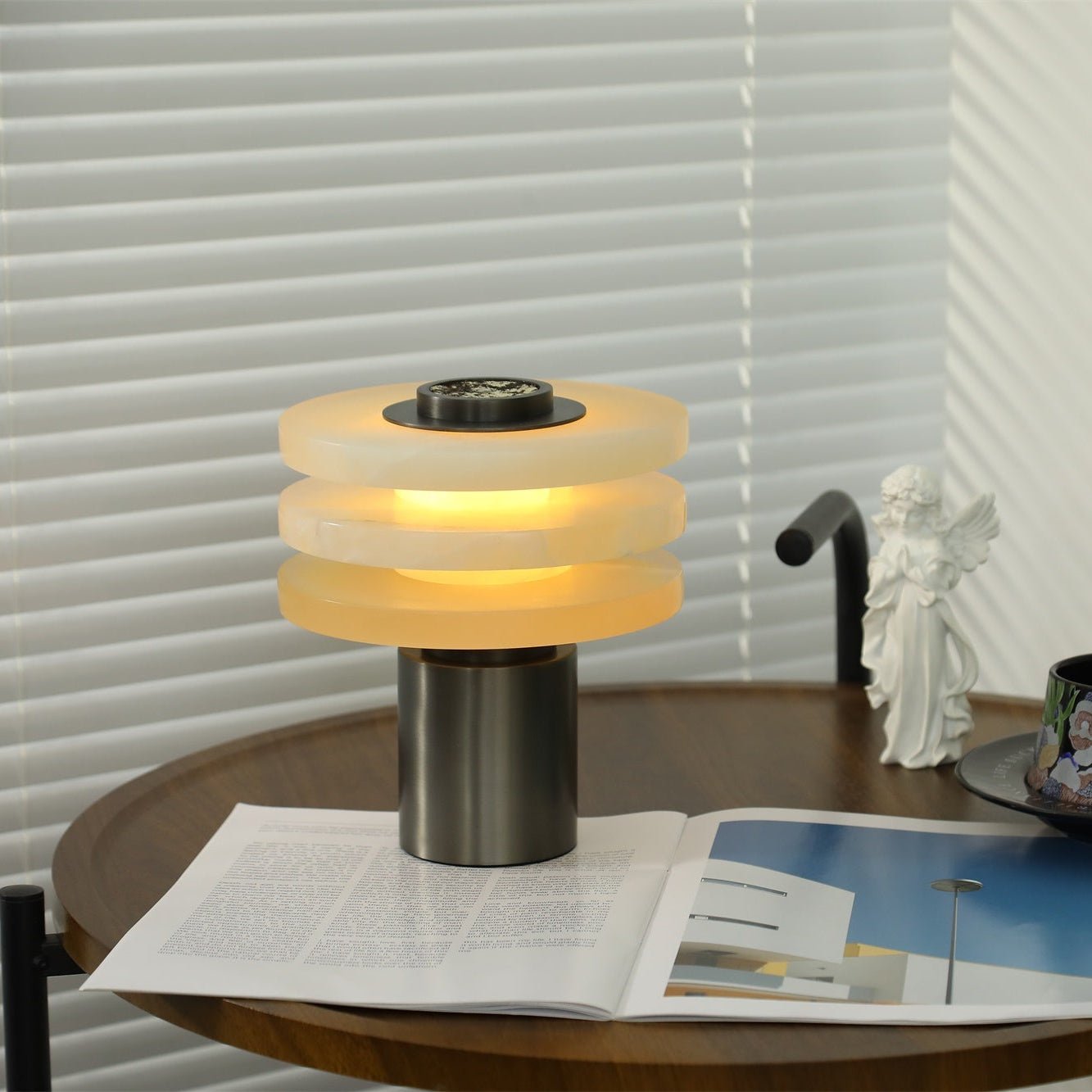 Side view of the lit lamp, three alabaster tiers separated by even bands of warm light