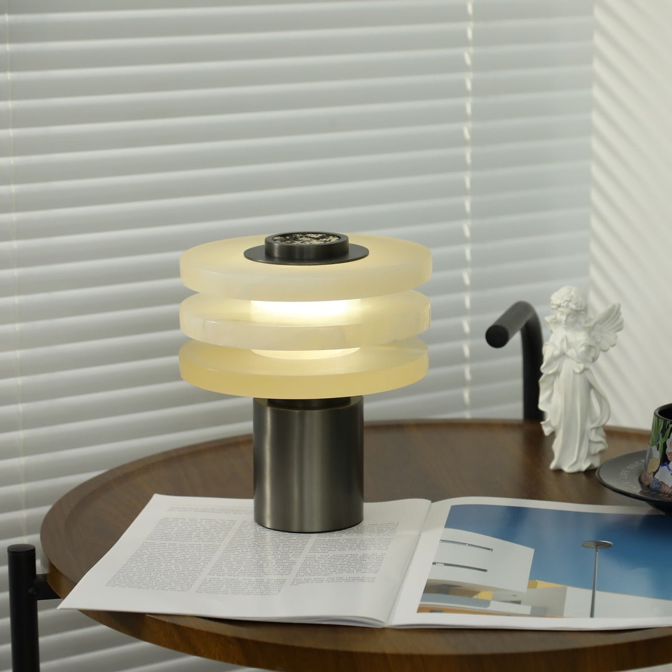 The lit alabaster lamp at an angle on the side table, its glow catching the veining in the stone tiers