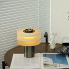 The alabaster lamp glowing softly in a reading corner, with venetian blinds and an angel figurine behind