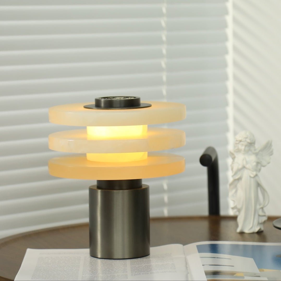 Close-up of the lit lamp showing the glowing core between the alabaster tiers and the brushed metal stem