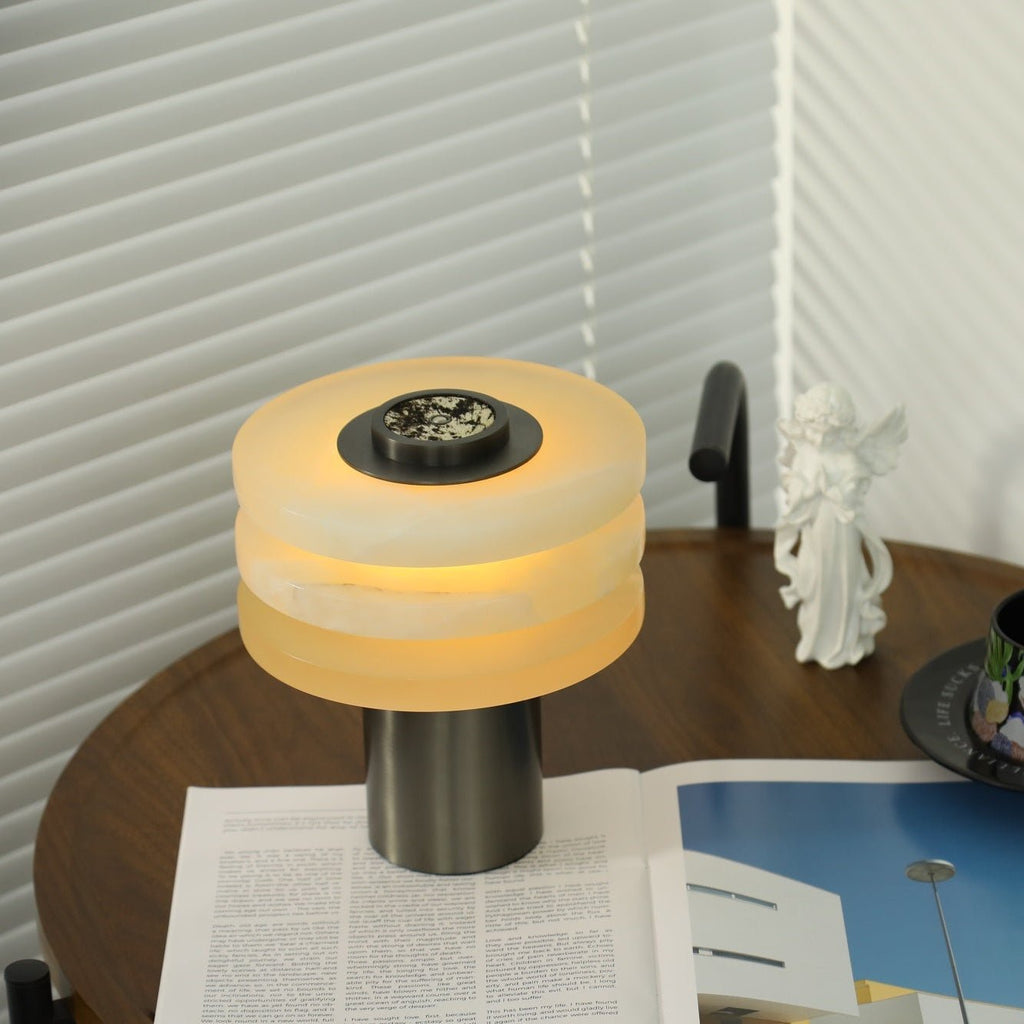 High-angle view of the lit lamp, its alabaster tiers drawn close together around the central metal dial