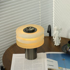 High-angle view of the lit lamp, its alabaster tiers drawn close together around the central metal dial