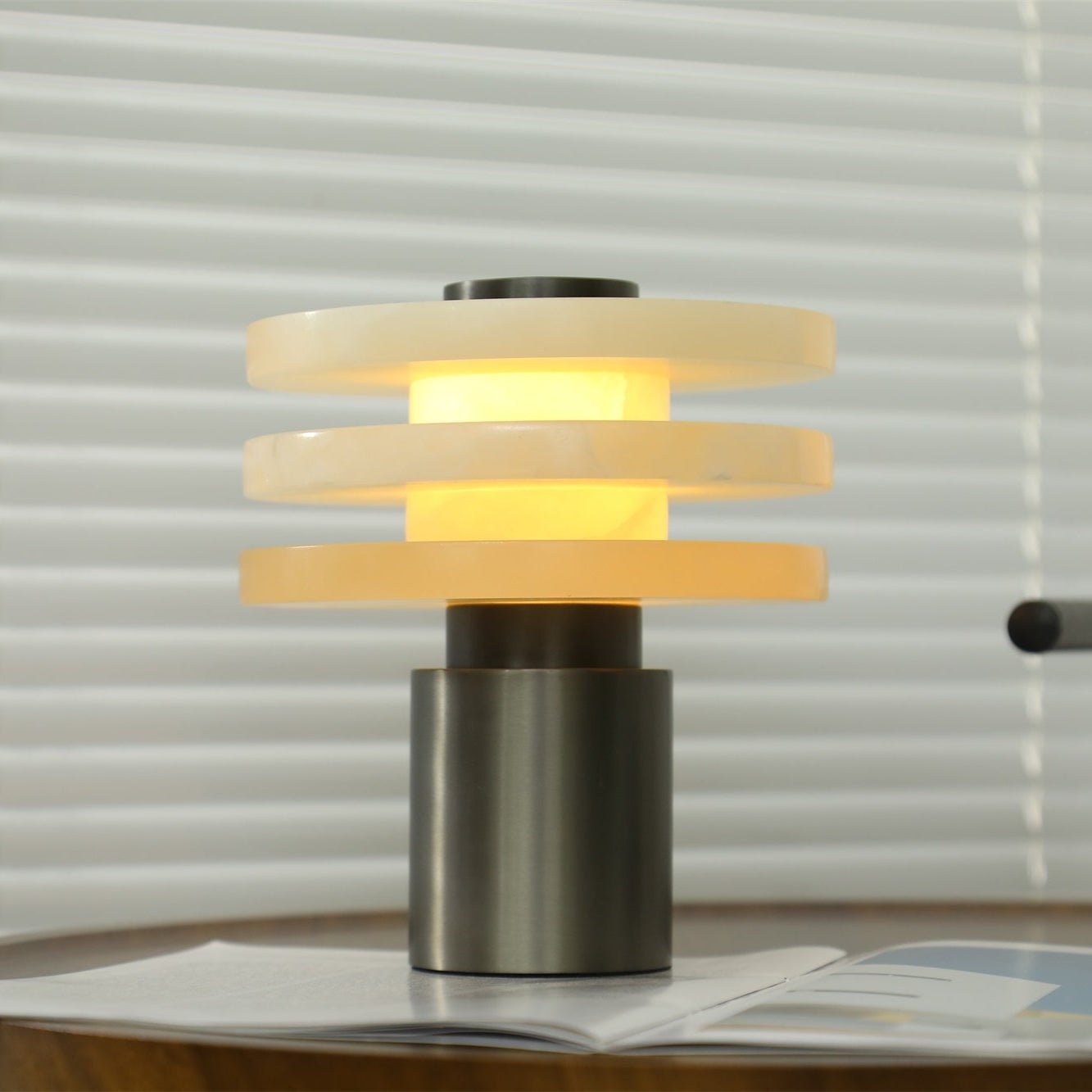 Close front view of the lit lamp, warm light escaping the wide gaps between its three alabaster discs