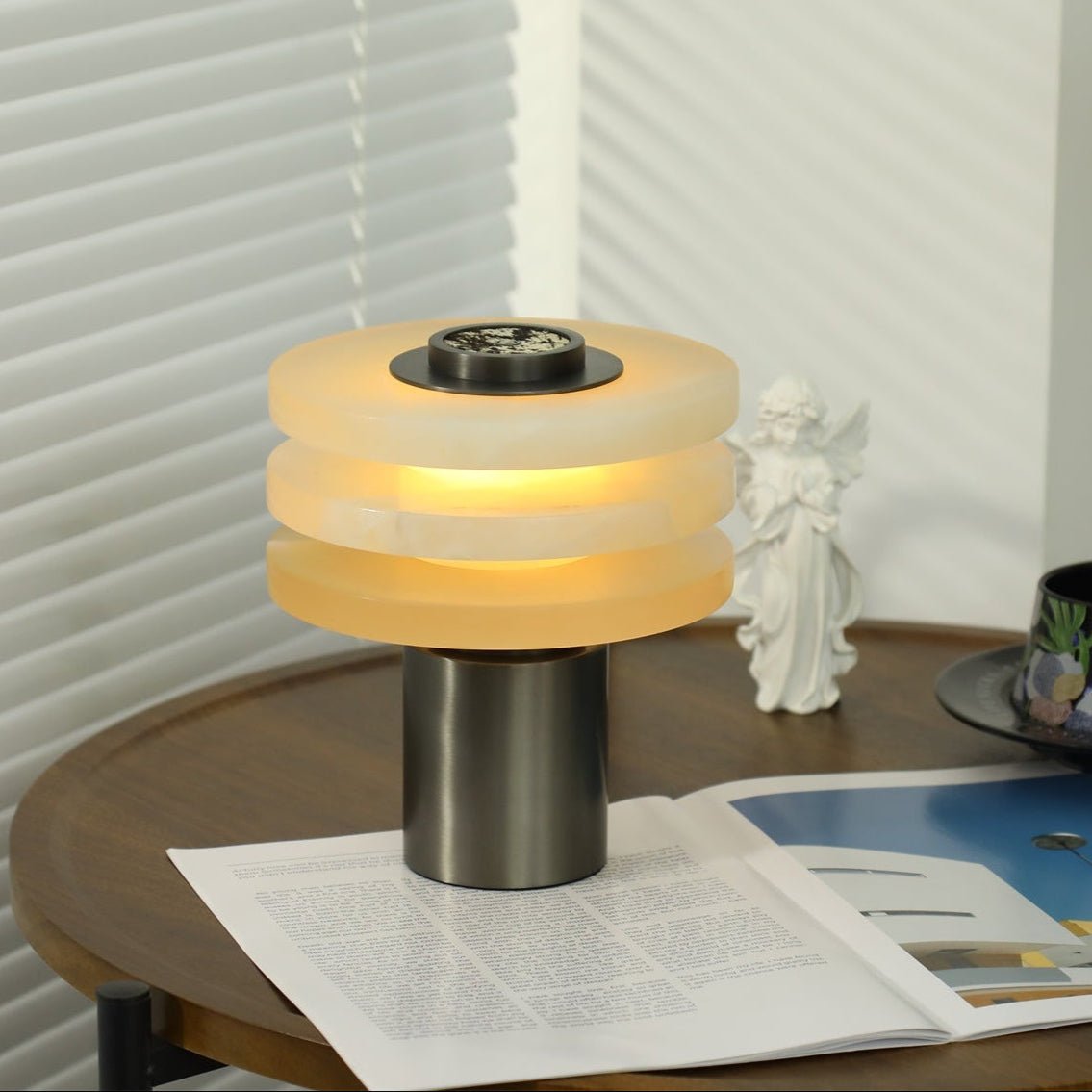 Eye-level view of the lit lamp, the brushed gunmetal cylinder base standing on an open magazine