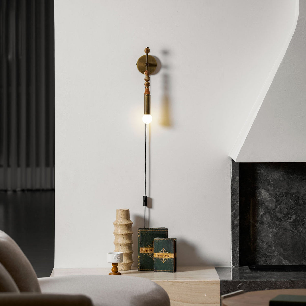 Clérachic wall sconce above the lounge table again, wood beads and a lit globe, a soft shadow cast beside it.