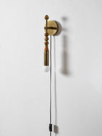 Clérachic wall sconce on a plain white wall, mixed bead shapes above a lit glass globe and hanging cord.