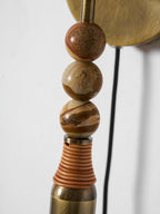 Close-up of three amber, tortoiseshell-patterned stone beads on a Clérachic wall lamp above a leather-wrapped tube.