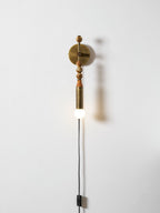 Clérachic wall light on a plain wall, mixed-size wood beads above a lit glass globe and a trailing cord.
