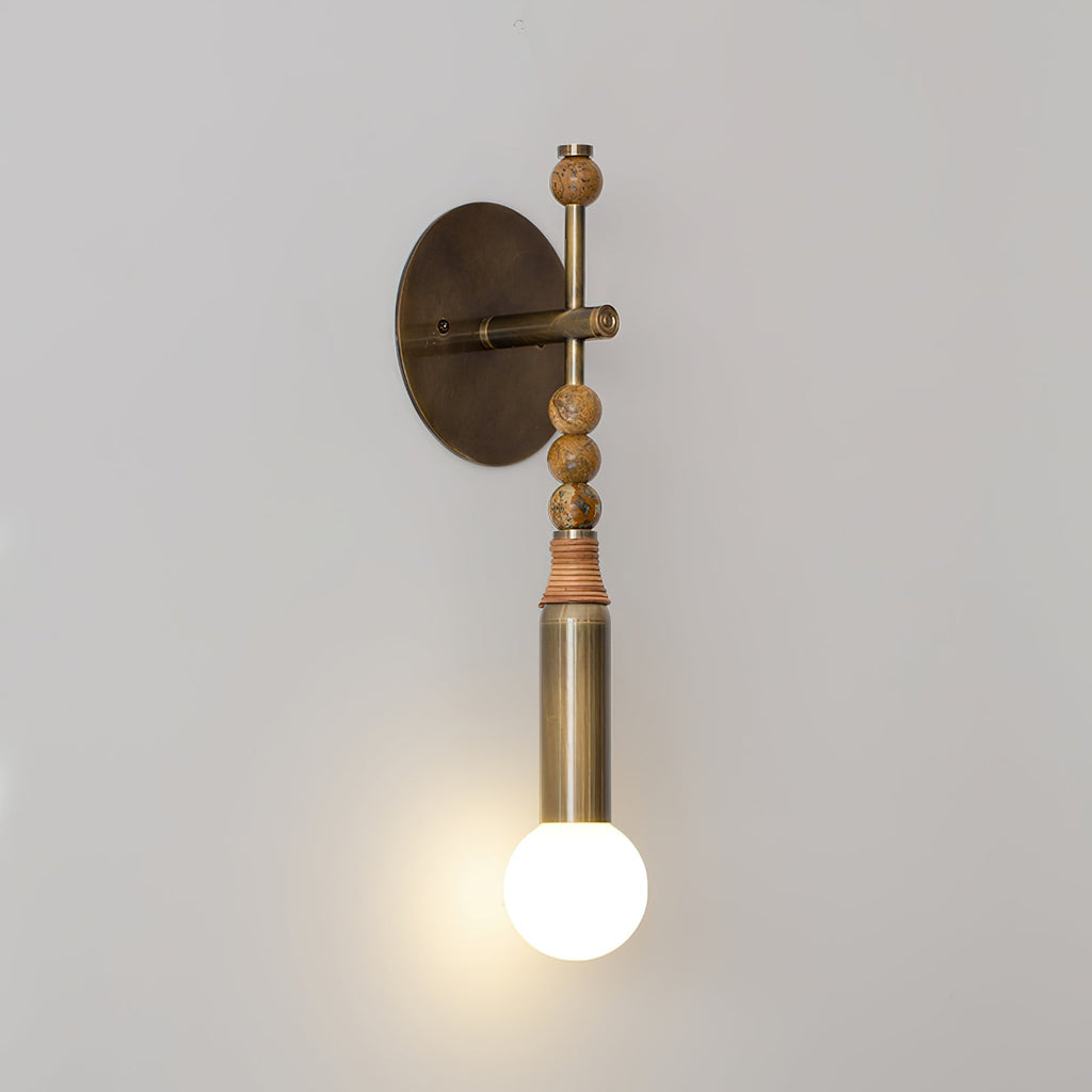 Antique brass wall lamp with warm glow beside framed art