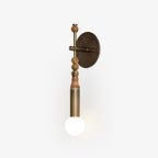 Antique brass wall sconce glowing in a styled bedroom