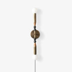 Clérachic wall light on white, a pale stone finial and grey beads above a lit glass globe, cord left loose.