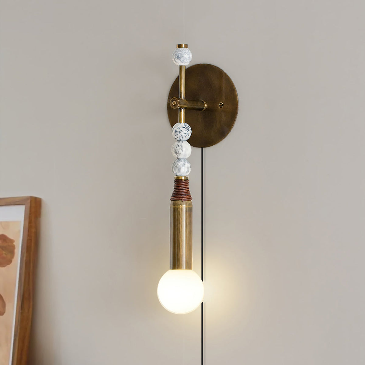Clérachic plug-in wall lamp beside a framed picture, wood and marbled beads above a lit globe and hanging cord.