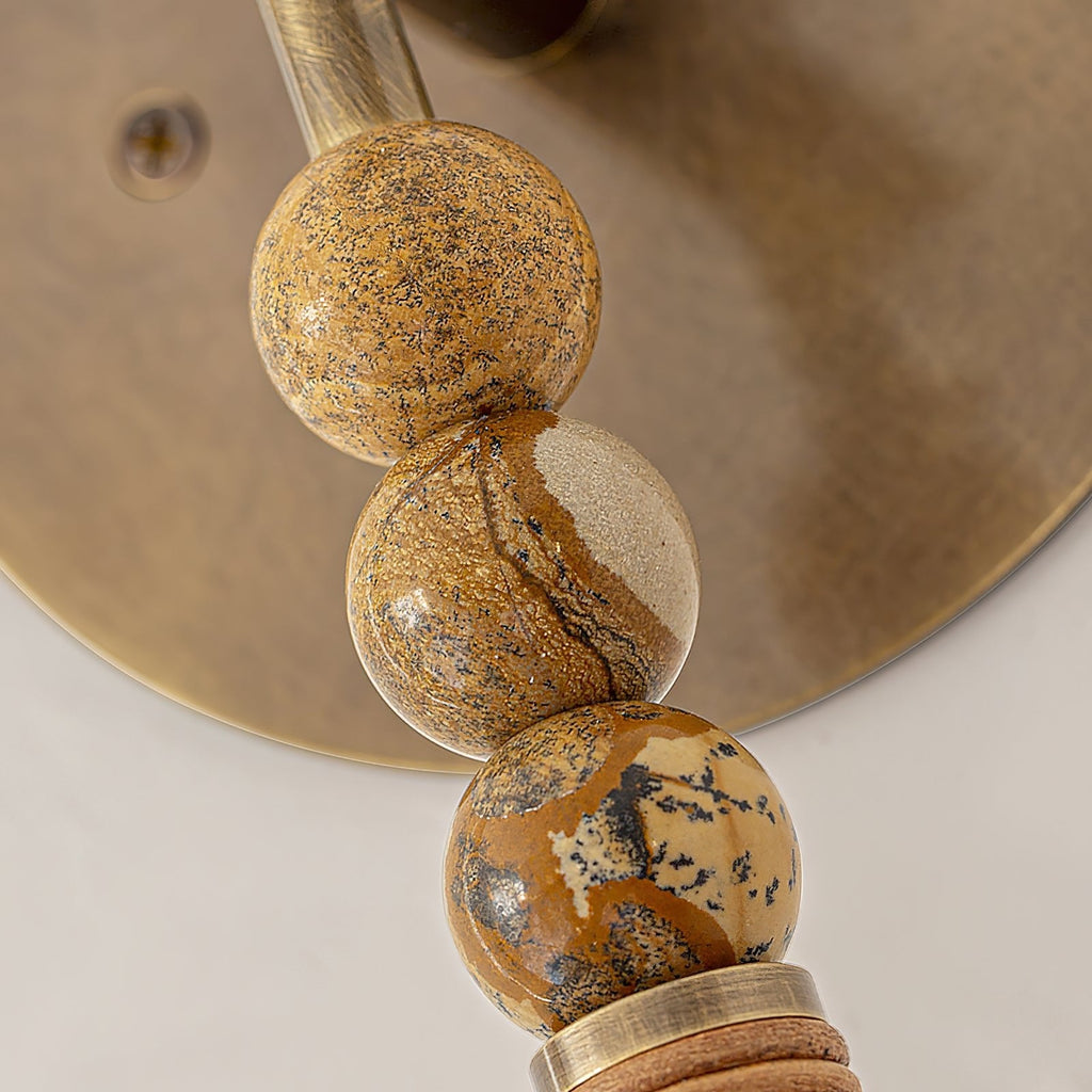 Brass wall sconce with marble accent lighting an entryway