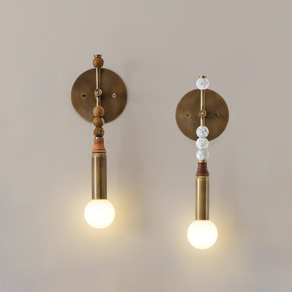 Brass wall sconce with marble detail beside a headboard