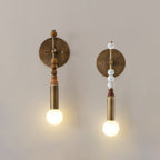 Brass wall sconce with marble detail beside a headboard