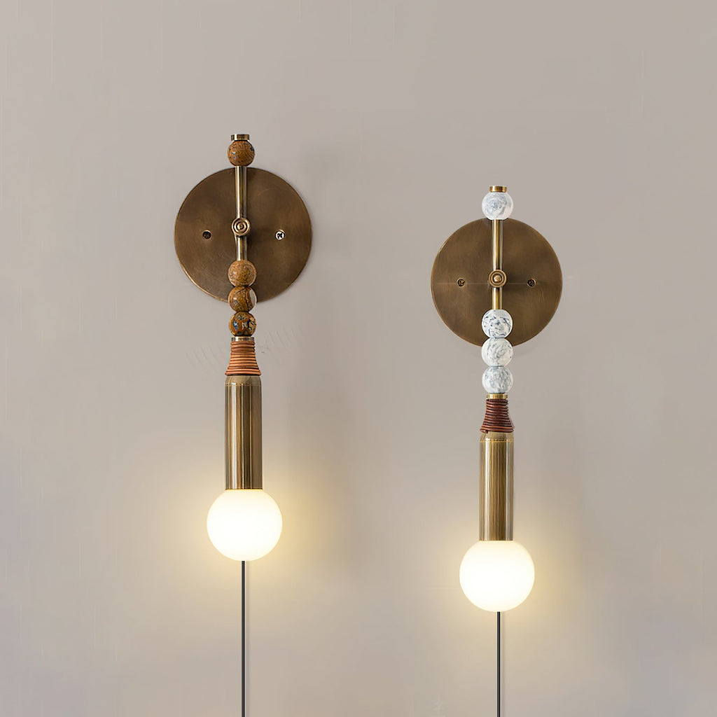 Two Clérachic wall sconce finishes compared on white: warm wood beads and pale marbled beads, both lit.