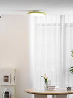 In a bright room with a round table holding books and a vase, this Clérachic ceiling light is mounted near the corner.