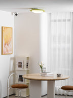 In the same bright room with a framed print and round table, this Clérachic ceiling light is mounted near the window.