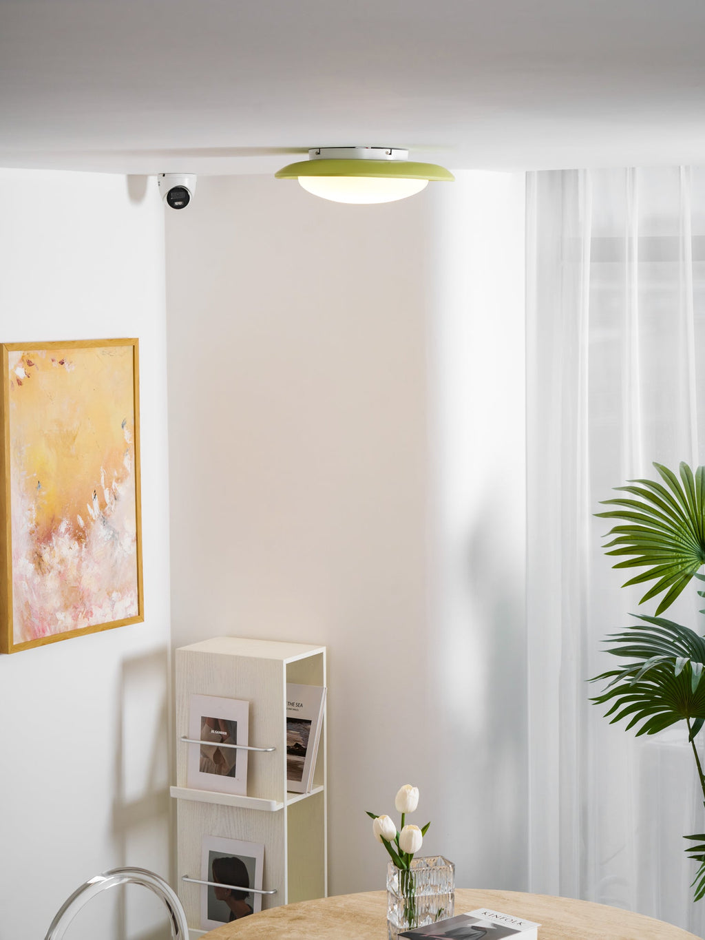 Below a framed print and beside a sheer curtain, this Clérachic ceiling light sits close to the ceiling corner.