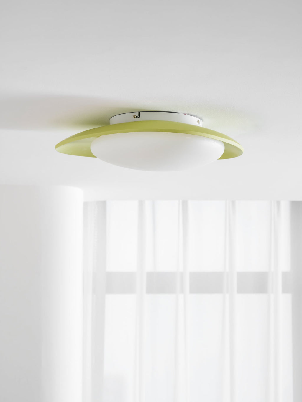 Seen from directly below, this Clérachic ceiling light's green rim and white diffuser glow near a sheer curtain.