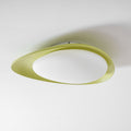 Seen from an angle, the green resin body of this Clérachic ceiling light frames a glowing oval diffuser.