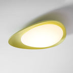 From a low angle on a plain backdrop, this Clérachic ceiling light's green rim glows warm around its diffuser.