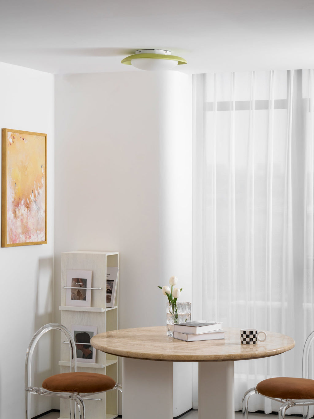 In a bright room with a framed print and a round table set with books and a vase, this Clérachic ceiling light sits in the ceiling corner.