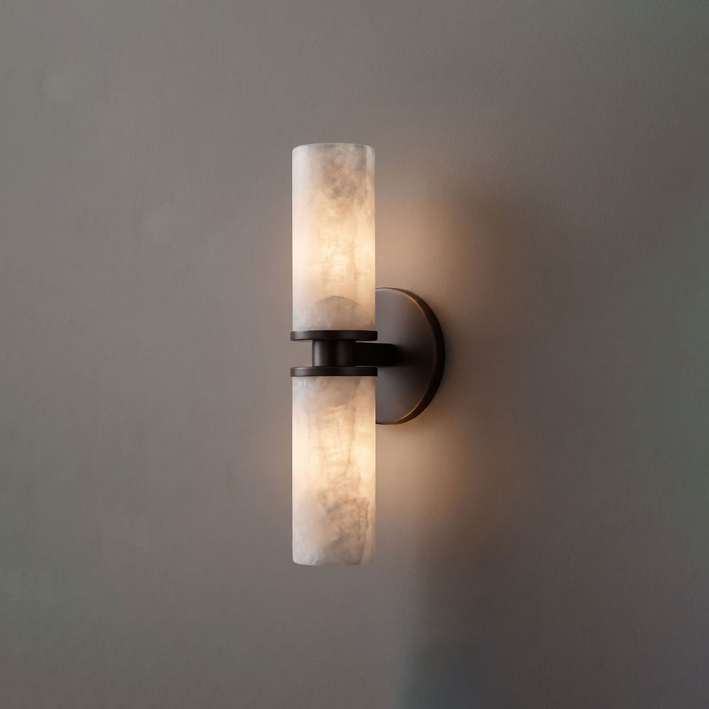 Close product view of this Clérachic wall light in matte black, its two alabaster tubes glowing against grey.