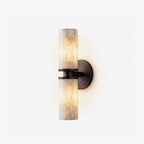 On a white backdrop, this Clérachic wall light in matte black shows its two lit alabaster tubes in full profile.