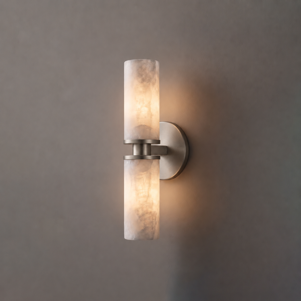 Close product view of this Clérachic wall light in brushed nickel, its two alabaster tubes lit against grey.