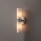 Close product view of this Clérachic wall light in brushed nickel, its two alabaster tubes lit against grey.