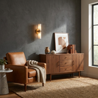 Above a leather armchair and a walnut credenza, this Clérachic wall light in matte black casts a warm glow.