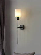 Clérachic dark bronze alabaster sconce lit beside a grey curtain, a soft cushion just below the frame
