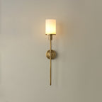 Clérachic brass alabaster wall sconce with a smooth opal shade, lit, on a soft beige wall