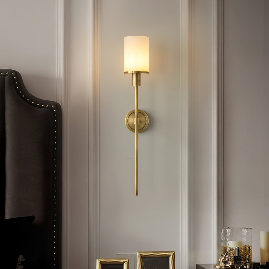 Clérachic brass alabaster sconce lit beside a studded headboard on a panelled bedroom wall